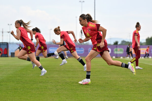 Four football players in kit, running on a football pitch
