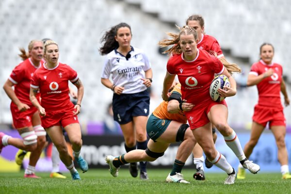 One rugby player in red kit is being tackled by other players in orange kit