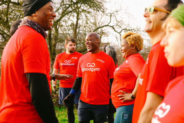 A group of GoodGym volunteers in red T-shirts smiling and chatting outdoors during a community run