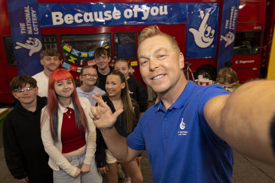 A man is taking a cross finger selfie with a group of young people.