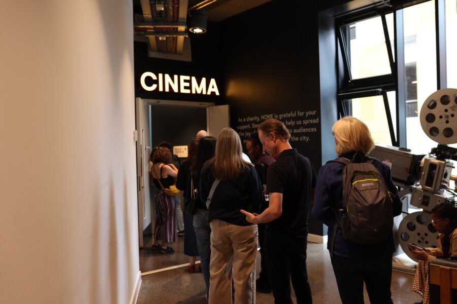 People queue up in front of a room with a sign that says 'cinema'.