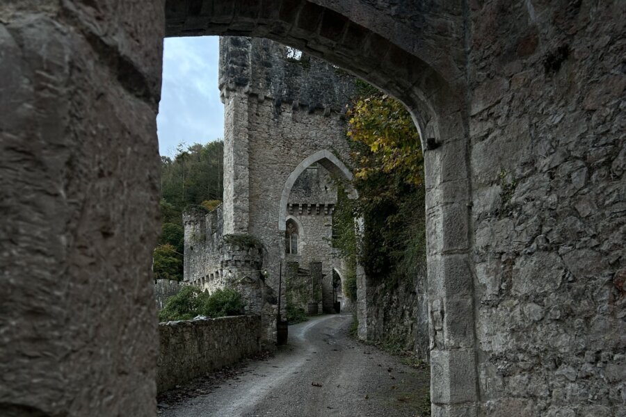 Stone castle walls and archway along a narrow path.