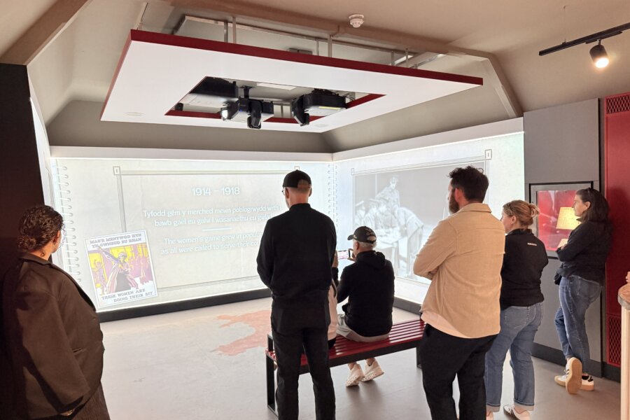 People stand in a room with a visual exhibition on the wall.