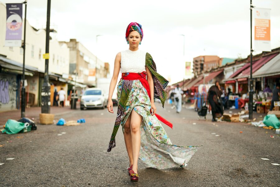 A woman walking trough Ridley Road wearing a beauitiful african outfit in London, England.