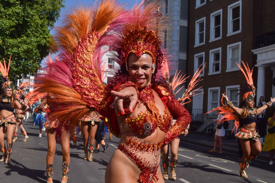 A lady in colourful carnival costume leads a group of dancers.