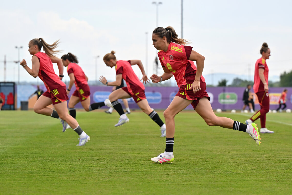 Four football players in kit, running on a football pitch