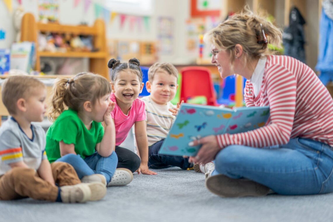 A group of children are being read a story by a teacher in a library.