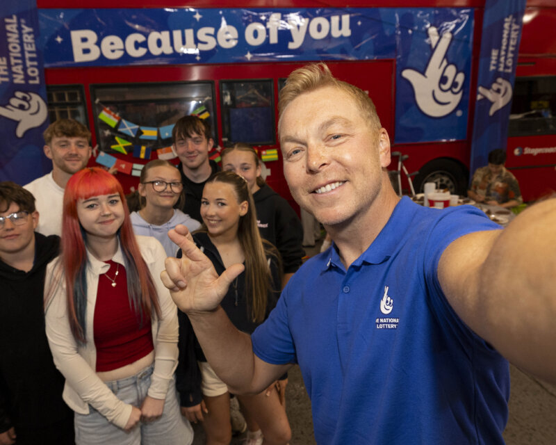 A man is taking a cross finger selfie with a group of young people.