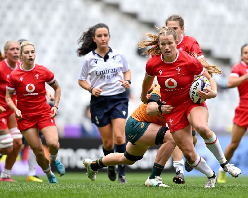 One rugby player in red kit is being tackled by other players in orange kit