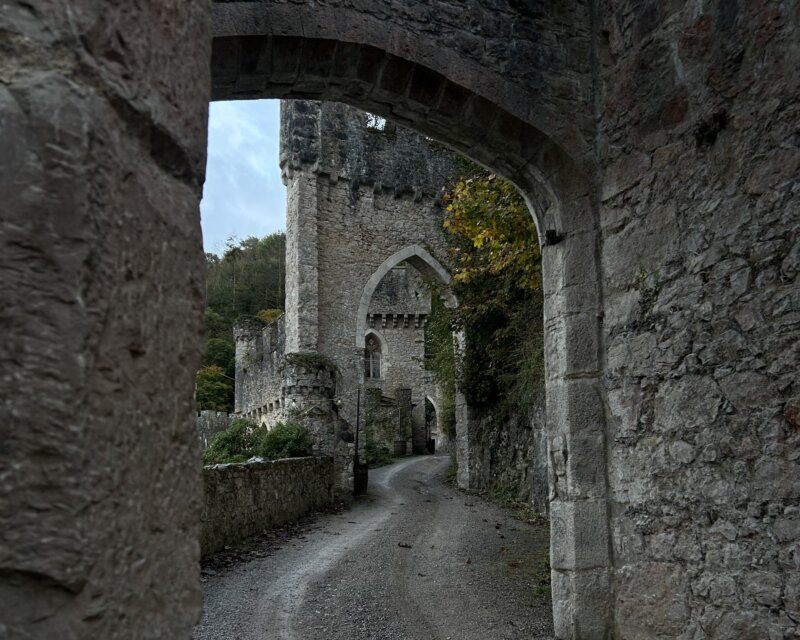 Stone castle walls and archway along a narrow path.