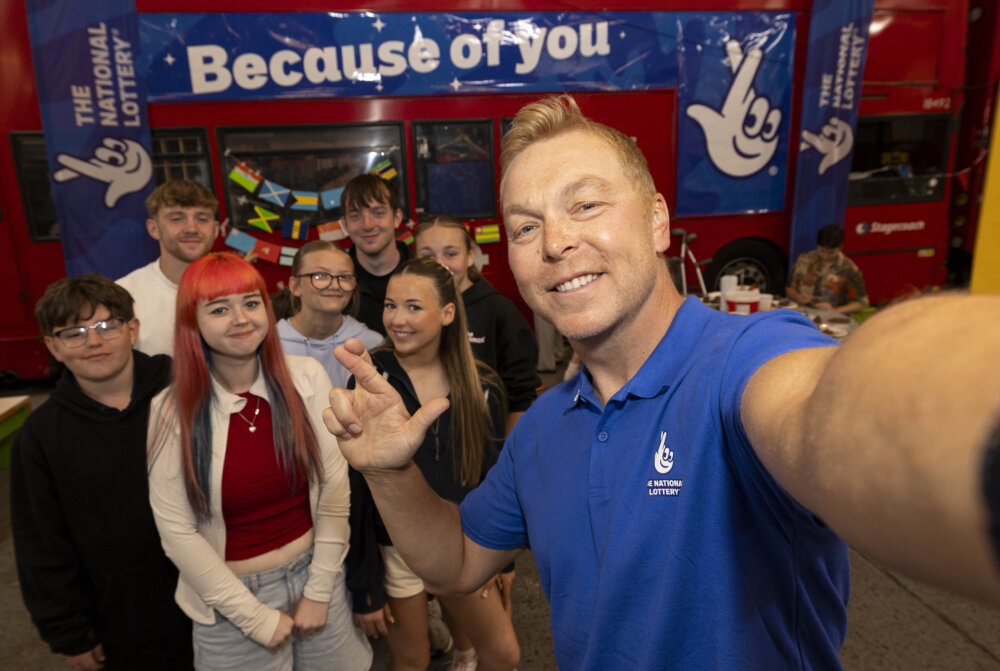 A man is taking a cross finger selfie with a group of young people.