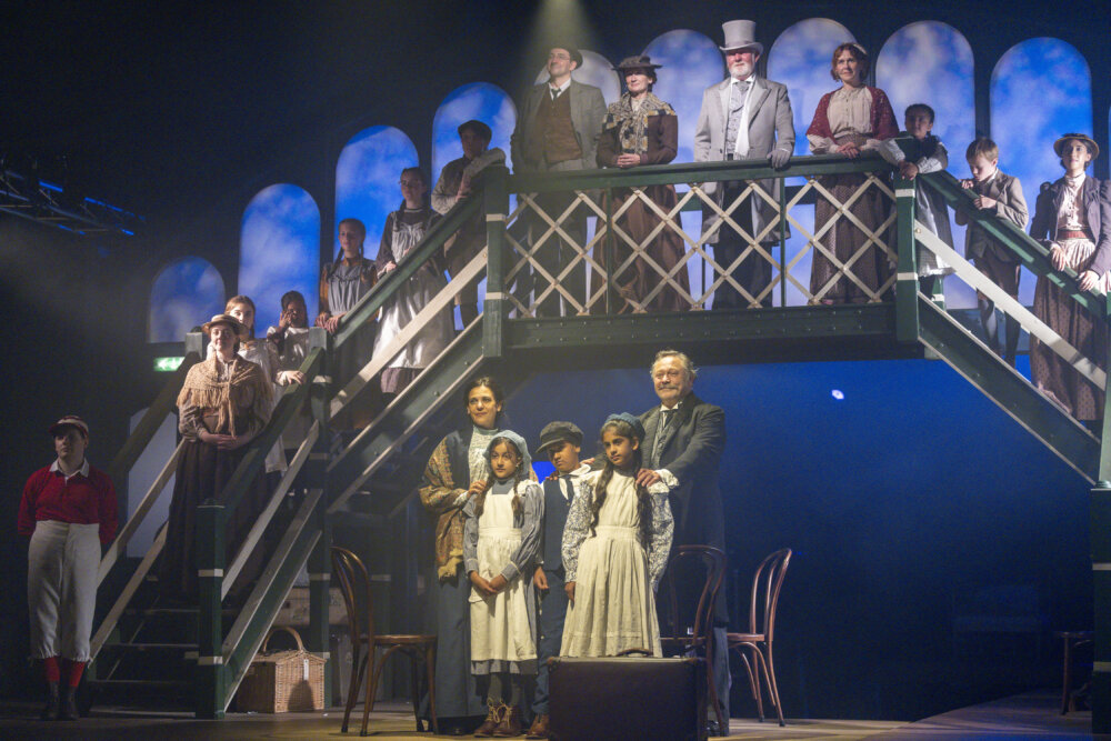 Cast members in period costume stand on a set of a reimagined Railway Children production.