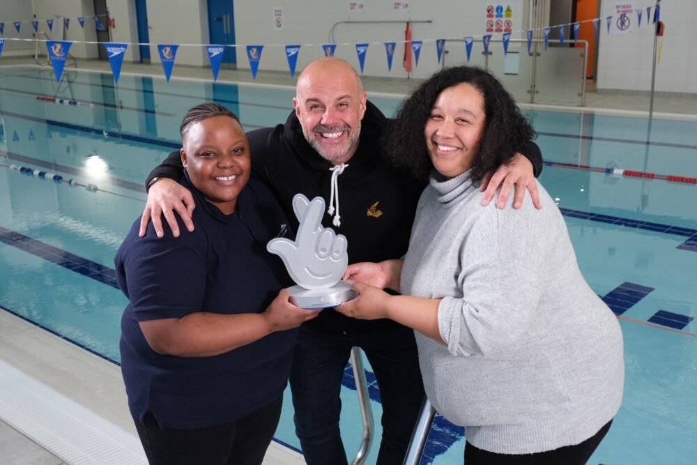 Jason Mohammad holding trophy with two members of the Black Swimming Association