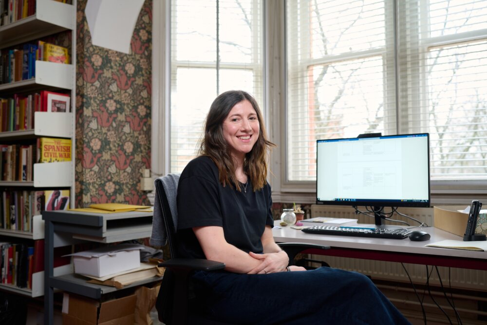 Photo showing Belinda Scarlett, Library Manager, sat at her desk inside the Working Class Movement Library