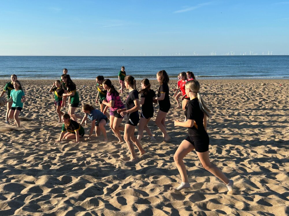 Young rugby players training on a beach.
