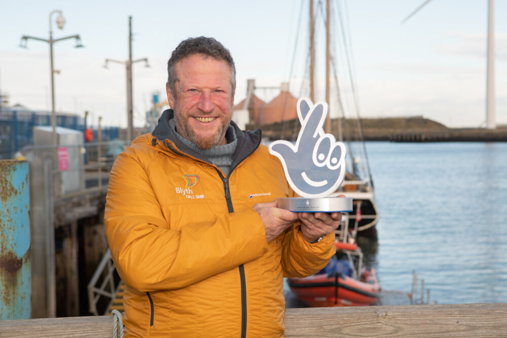 A person (Clive Gray) holding a National Lottery Awards trophy