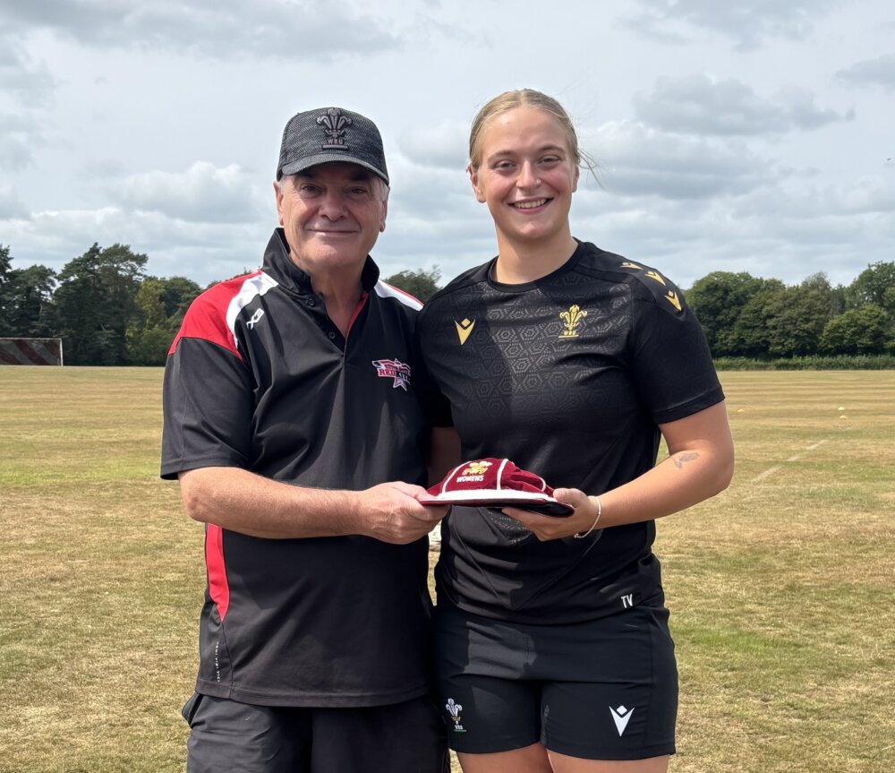 Two rugby players in black jerseys posing for a photo.