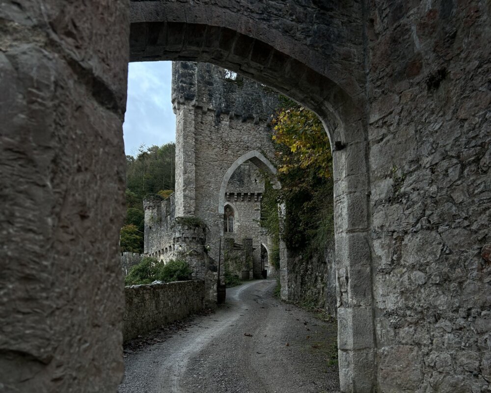 Stone castle walls and archway along a narrow path.