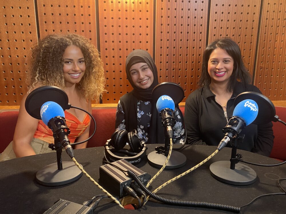 Three women (Amber, Taiba and Kiran) in a podcast recording venue.