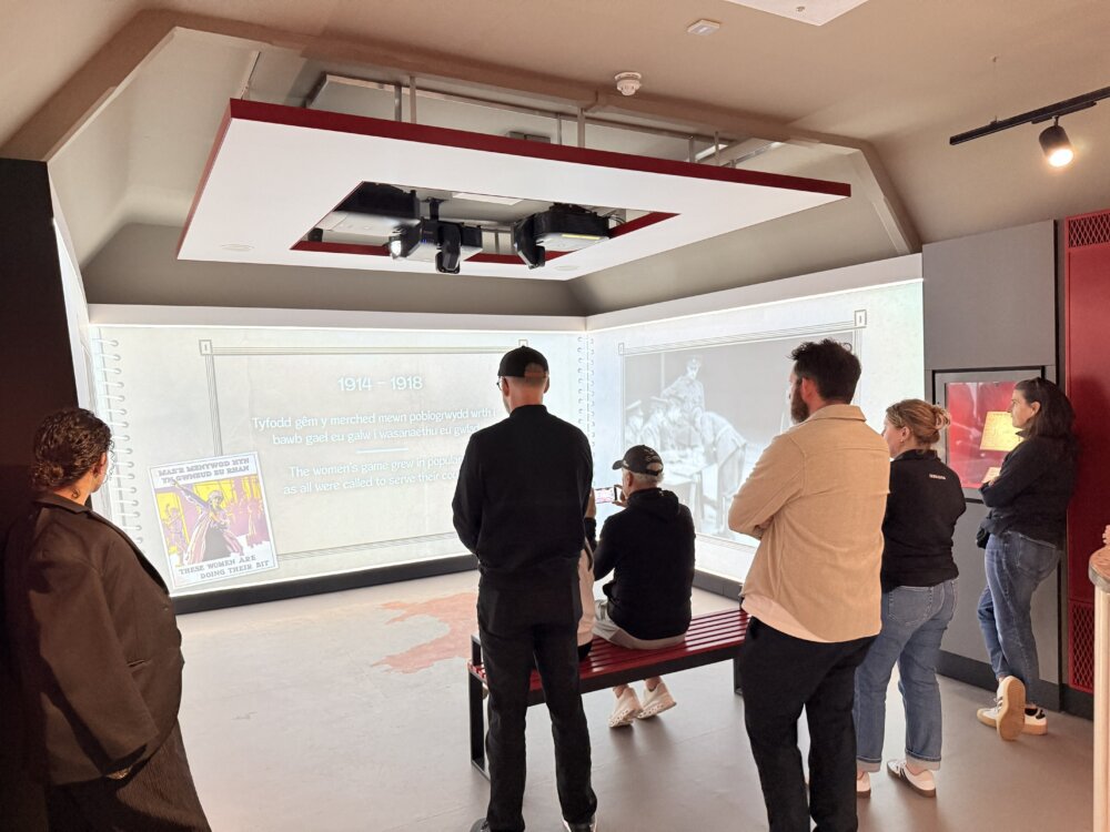 People stand in a room with a visual exhibition on the wall.