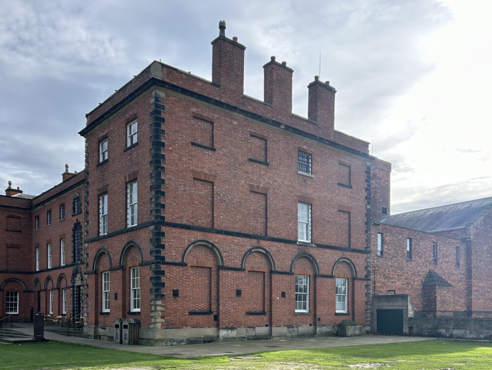 A red brick building set within a grassy landscape.