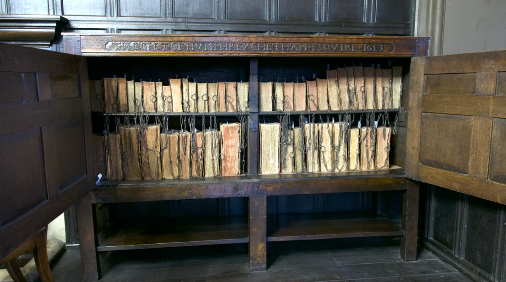 Photo of a cabinet, doors open, revealing 17th-Century books under lock and key, chained up - the gift of the original owner Sir Humphrey Chetham in 1655.