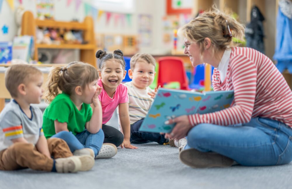 A group of children are being read a story by a teacher in a library.
