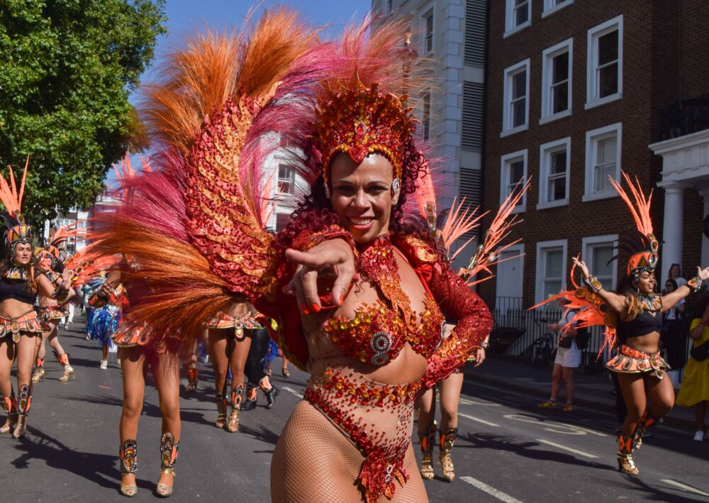 A lady in colourful carnival costume leads a group of dancers.