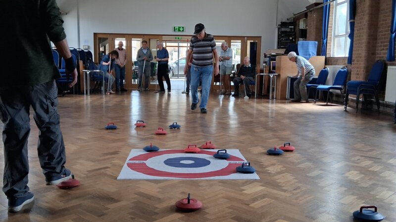 A group enjoys a game of indoor curling, a.k.a. new age kurling. (Picture courtesy of The Elder Tree)