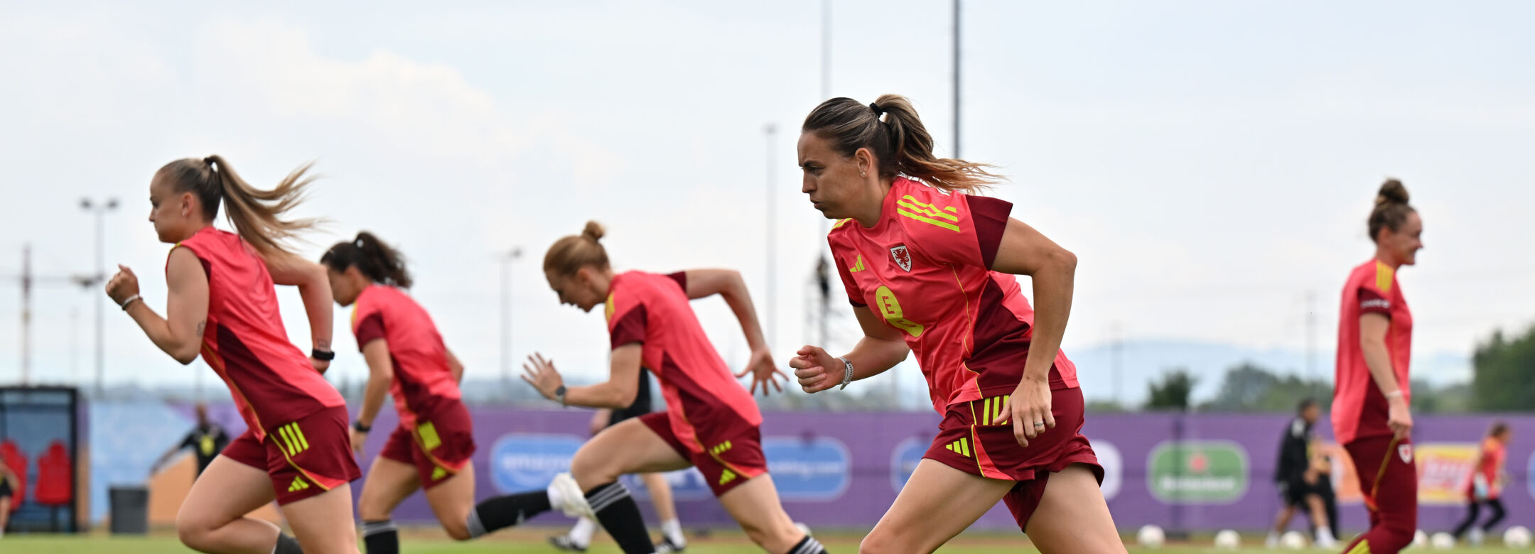Four football players in kit, running on a football pitch