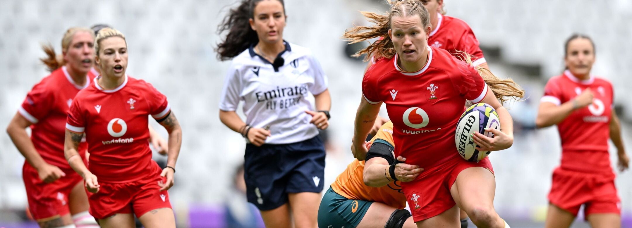 One rugby player in red kit is being tackled by other players in orange kit