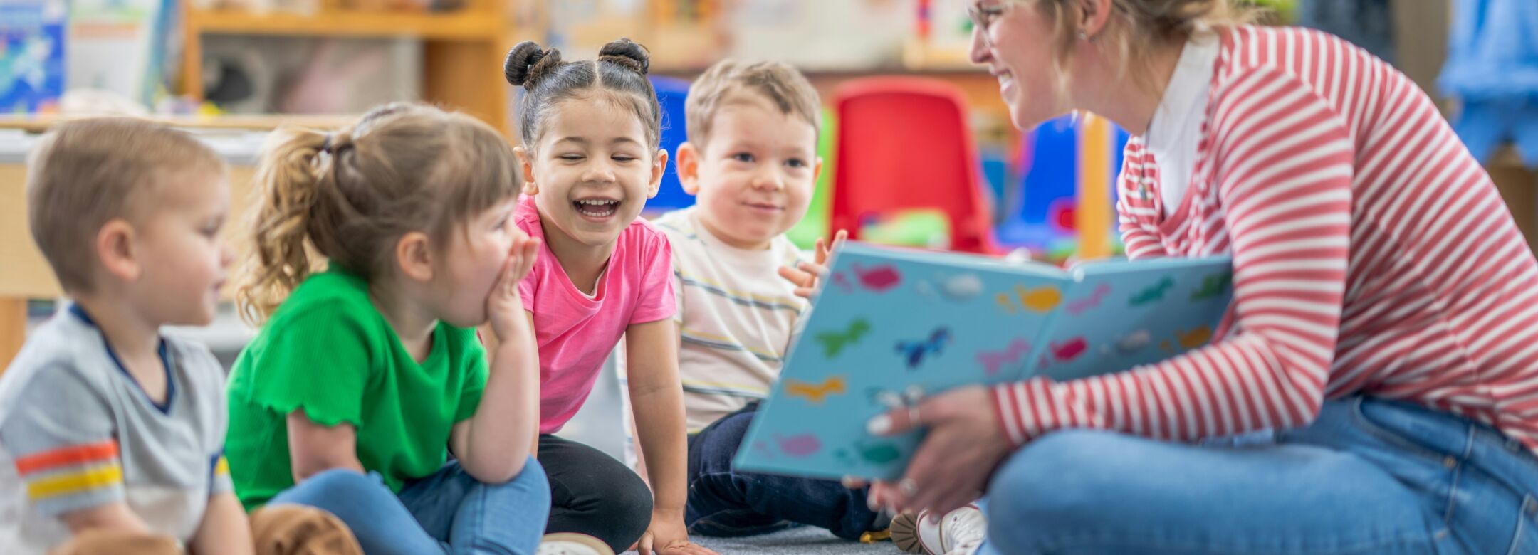 A group of children are being read a story by a teacher in a library.