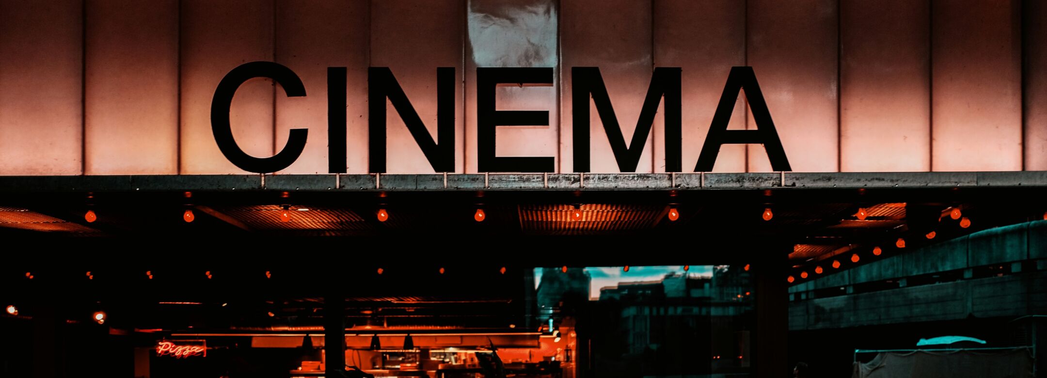 A image of bar at night with red lights and a sign that says "cinema".
