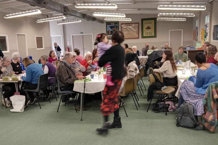 Room with tables and people seating eating a meal