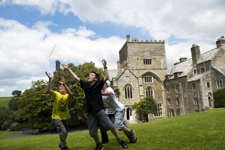 Children playing frisbee in the garden at Buckland Abbey, Devon.