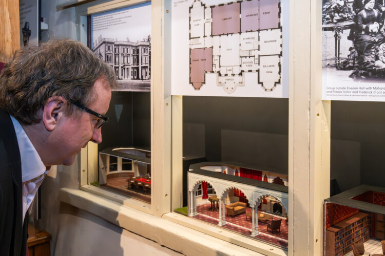 A white man looks at miniature dolls house size recreations of rooms at Elveden Hall.