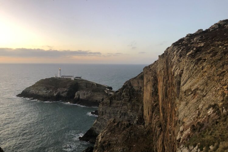 Alt=“The sea with a steep rocky cliff and lighthouse"