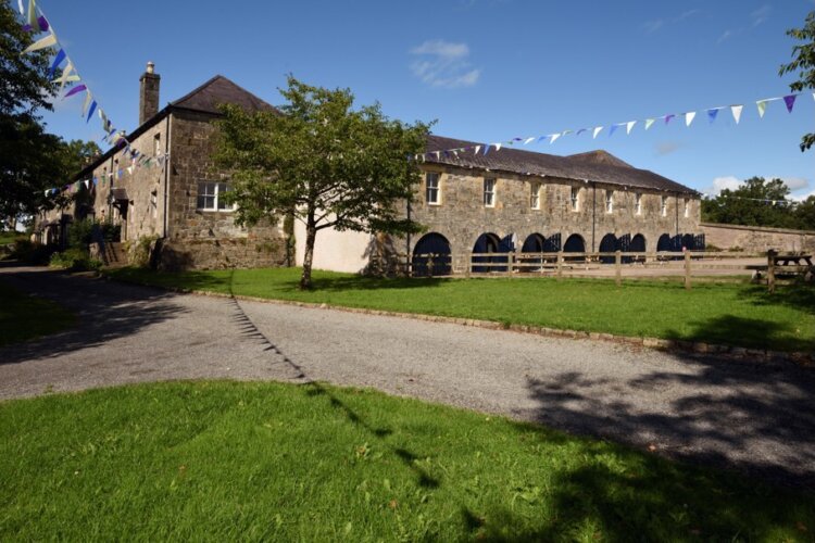Blue and white bunting lines the garden in front of a long stone building
