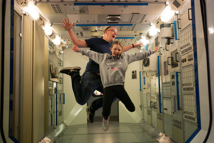 Two people pictured playfully floating inside a space station at National Space Centre.