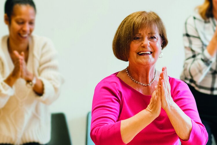 A woman smiling and dancing, two other dancers are with her