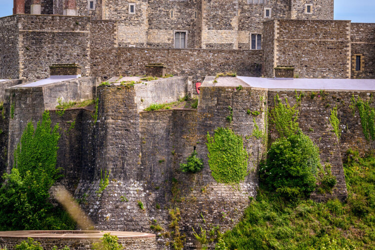 Ancient stone fortress wall with lush green ivy climbing its surface. The historic structure conveys a sense of strength and timelessness.