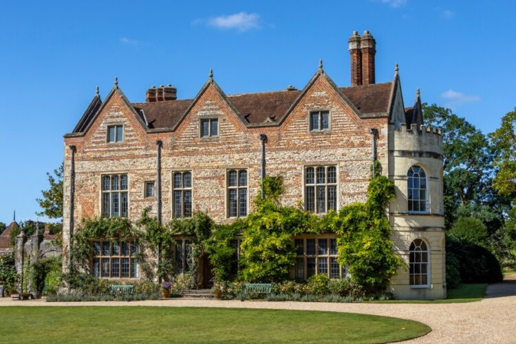 A large country house with greenery growing on the lower half