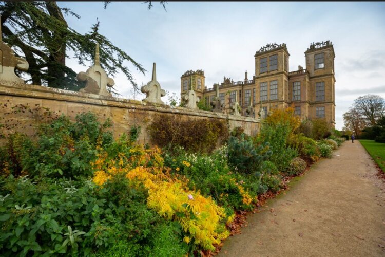 View along the herbaceous border leading up to a large castle like hall