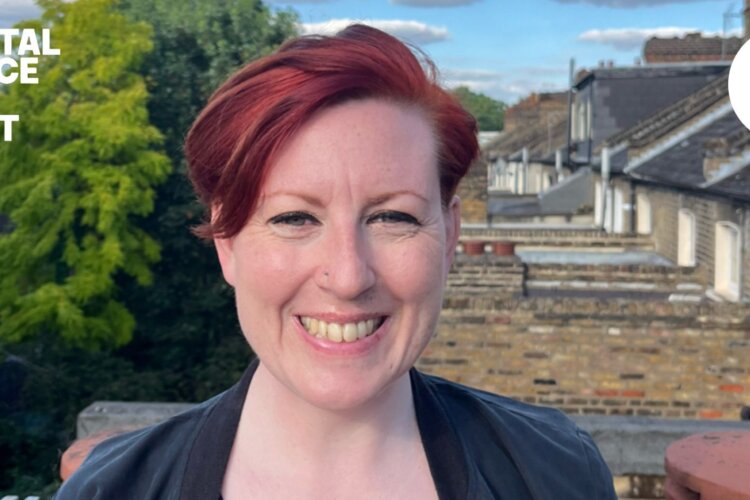 A photo of the walk leader, local guide Nikki Catto. She stands smiling in front of the roofs of terraced houses
