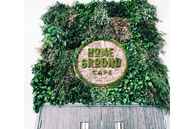 A black door with a living wall above it that says 'HomeGround'.