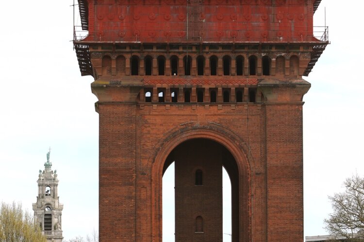 A tall red brick tower with a green roof.