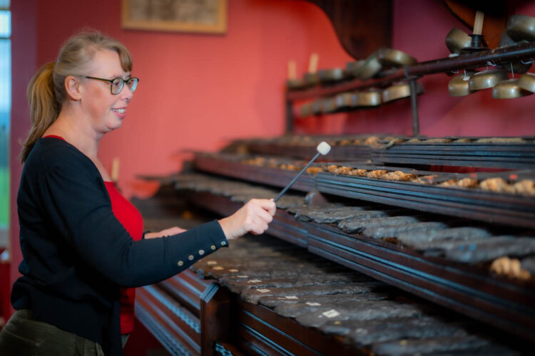 A woman with glasses playing musical stones with a large stick