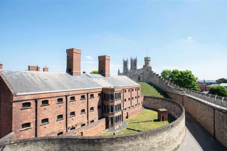 A red brick building is surrounded by walls, as well as an outer castle wall.