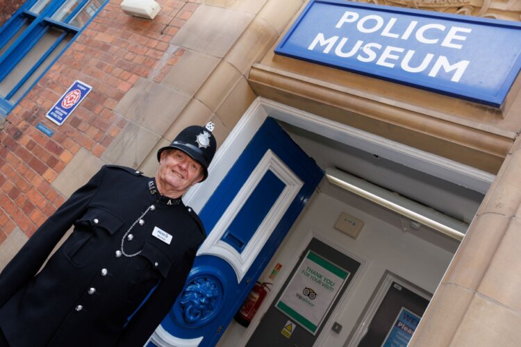 Front entrance of the Greater Manchester Museum, with museum volunteer stationed out front in original uniform.