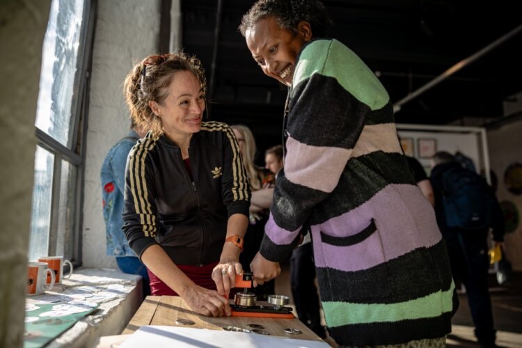 Two people smiling as they use a badge maker